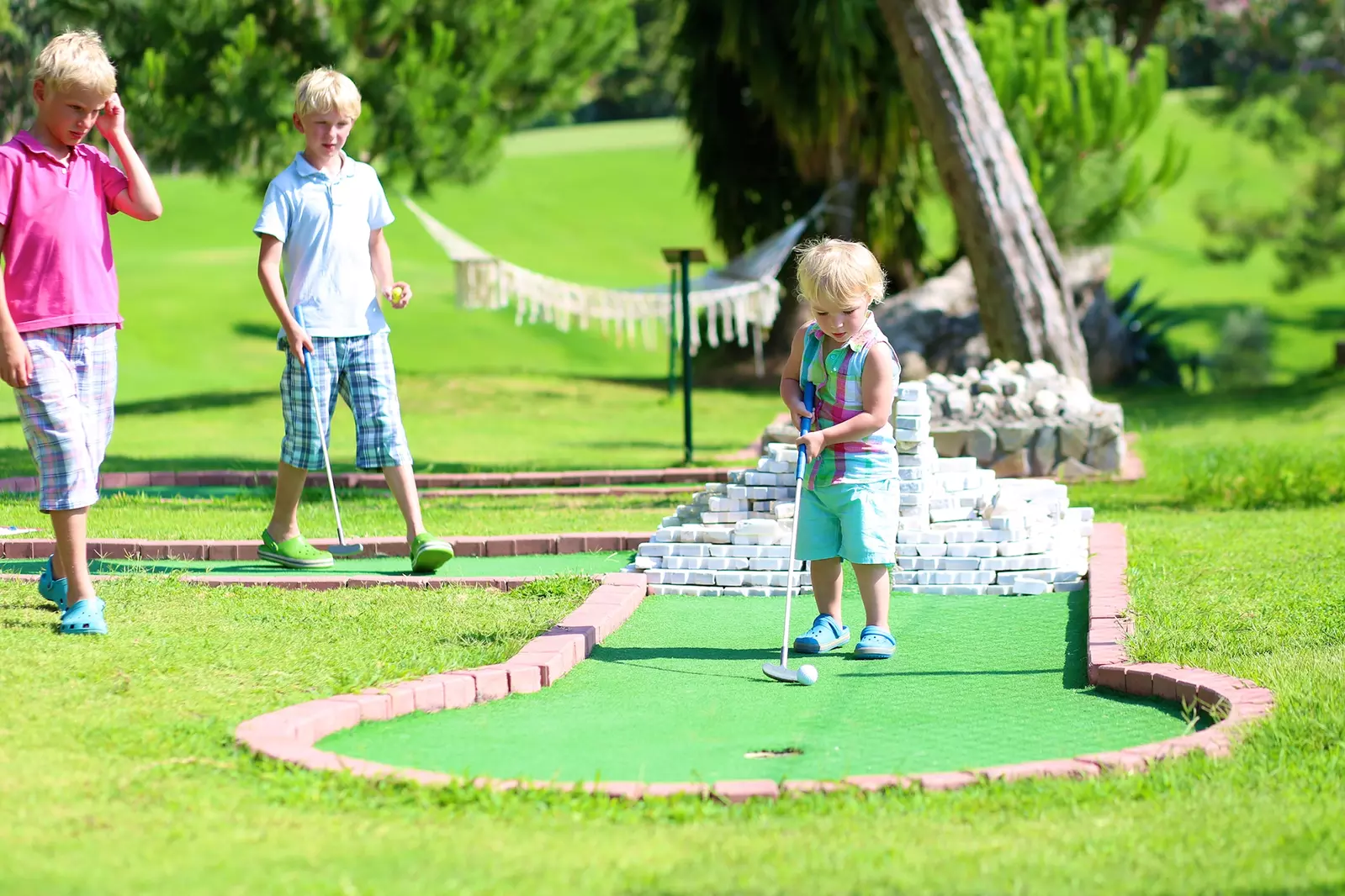 three boys playing miniature golf